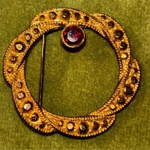 Avon 80s costume jewelry gold tone circle pin with marcasite garnet stone.